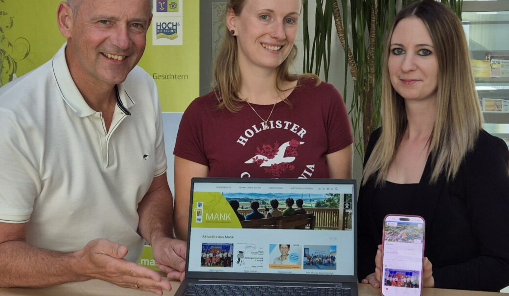 BGM DI Martin Leonhardsberger freut sich zusammen mit Regina Kaiser und Katharina Seidl &uuml;ber die hohen Zugriffszahlen auf die Gemeindewebseite und zeigt diese auf einem Notebook, Katharina Seidl auf einem Smartphone